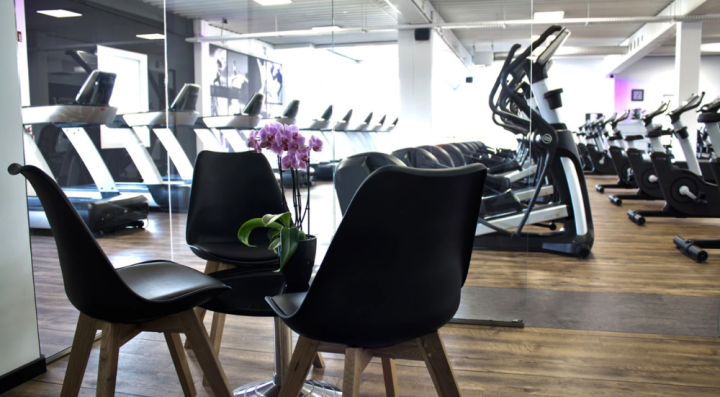 Moderne fitnesscenter med løbebånd, elliptiske maskiner og træningscykler i et åbent træningslokale