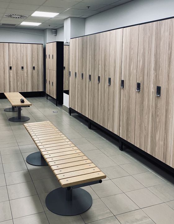 Omklædningsrum med træbænke og garderobeskabe til fitnesscenter eller sportshal