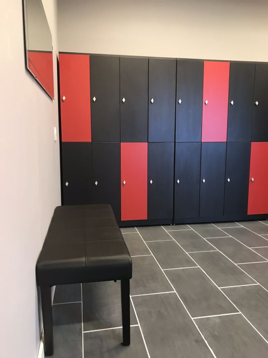 Moderne omklædningsrum med skabe, bænk og flisegulv til fitnesscenter