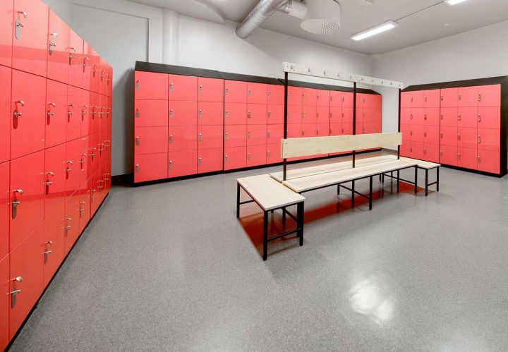 Omklædningsrum med røde skabe og bænk til fitnesscenter eller træningsfacilitet