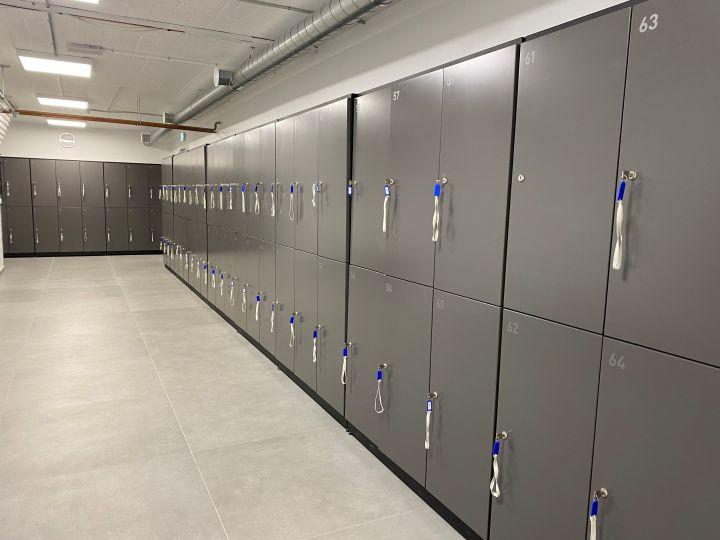 Opbevaringsskabe til fitnesscenter med nummererede låger og hængelåse i en lang gang