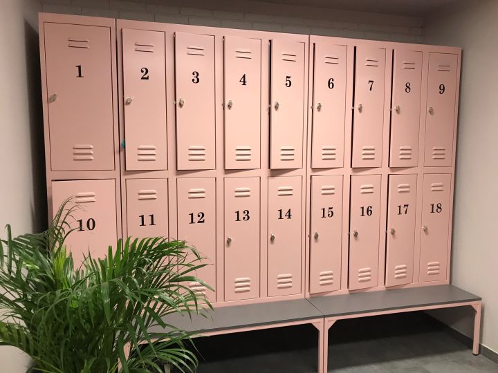 Pinke opbevaringsskabe til omklædningsrum i fitnesscenter med nummererede låger og bænke